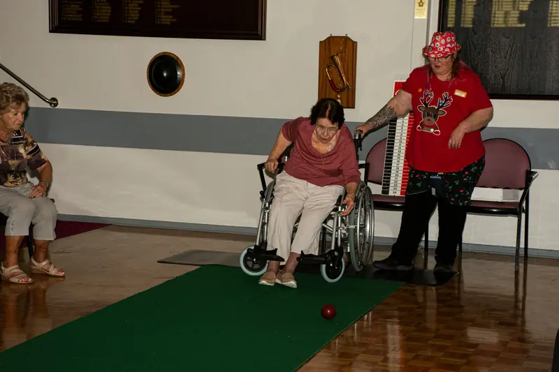 A member bowling from her wheelchair on the carpet lane