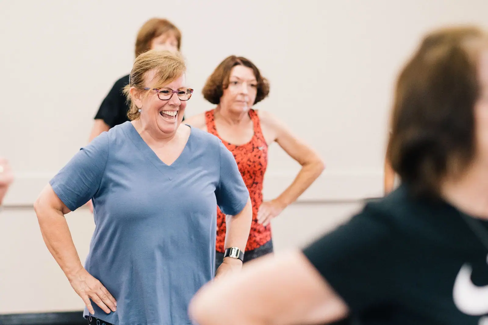 Members laughing together mid-routine during the morning dance class on the floor