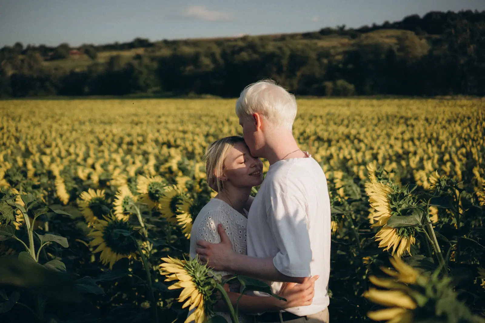A member and his wife standing in the sunflower row behind the center on a late summer evening