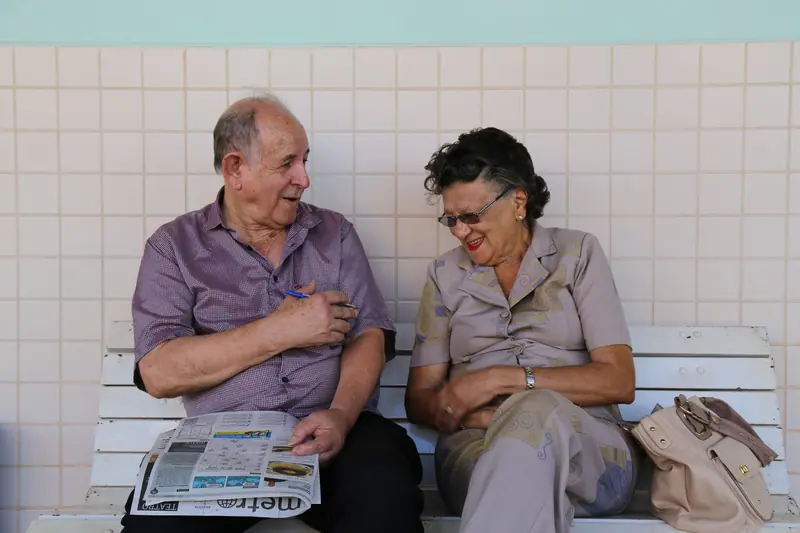 Two friends sharing the newspaper on a bench