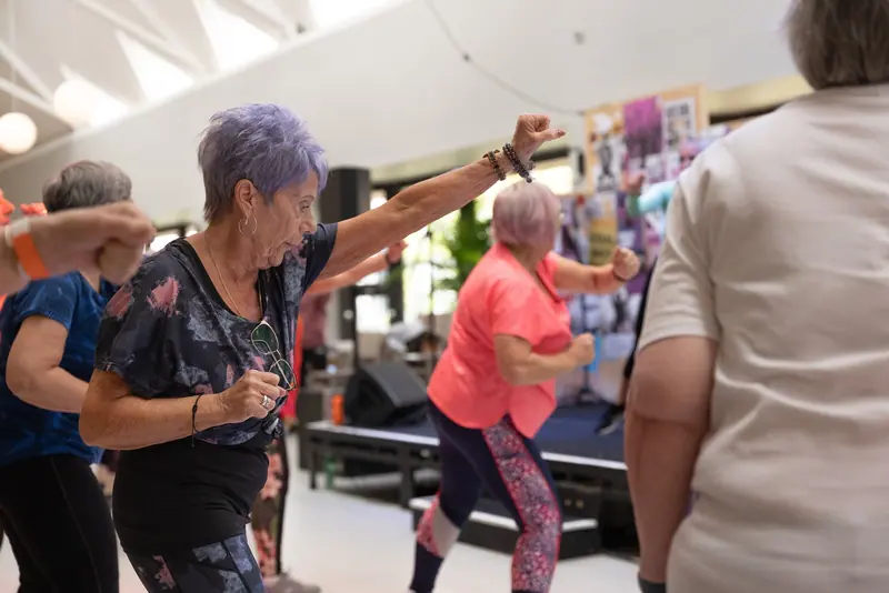 Two members dancing with headphones during music hour