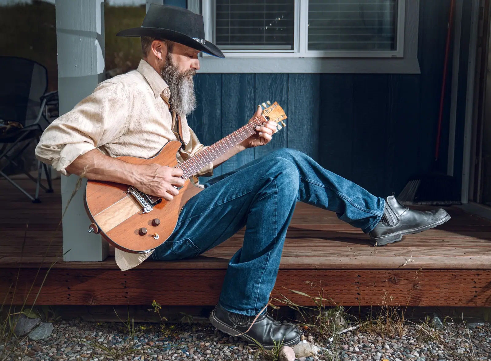 A member playing guitar on the porch of the barn in the afternoon sun