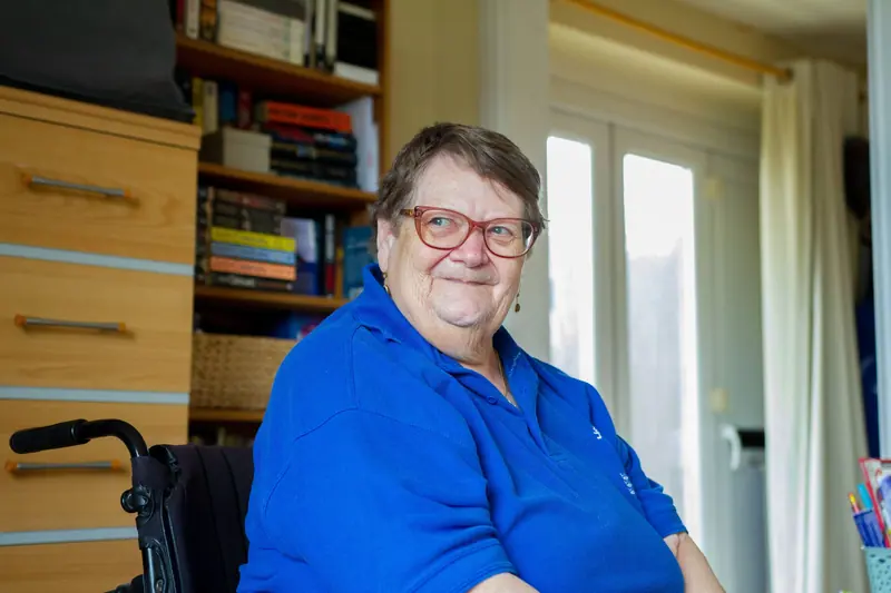 A member smiling in her wheelchair in the reading corner
