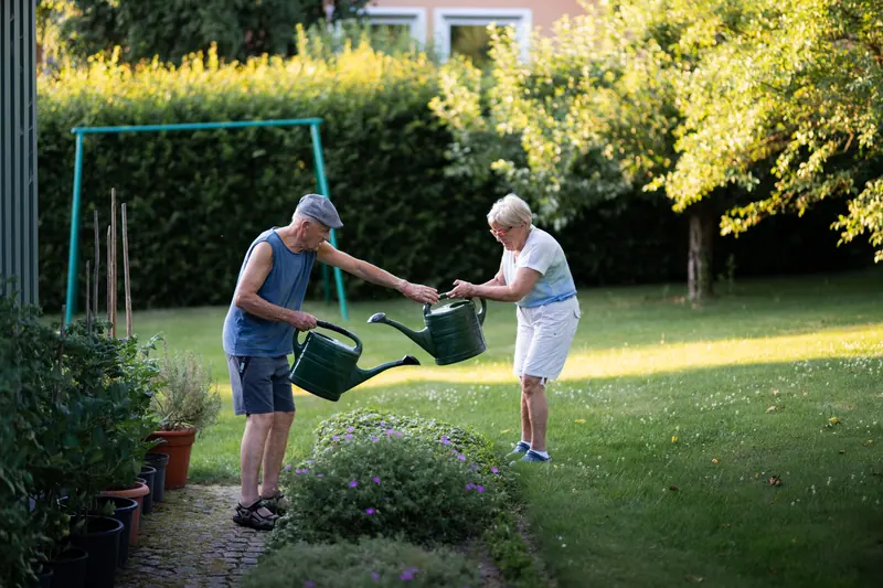Two members watering the garden behind the farmhouse
