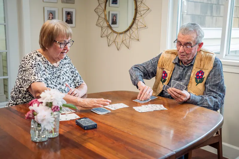 A couple playing cards at a wooden table after lunch