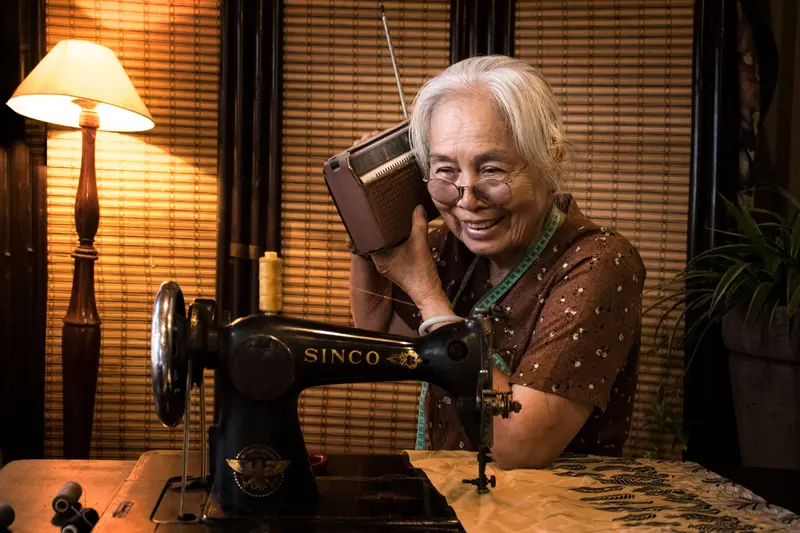 A member listening to the radio at her sewing table