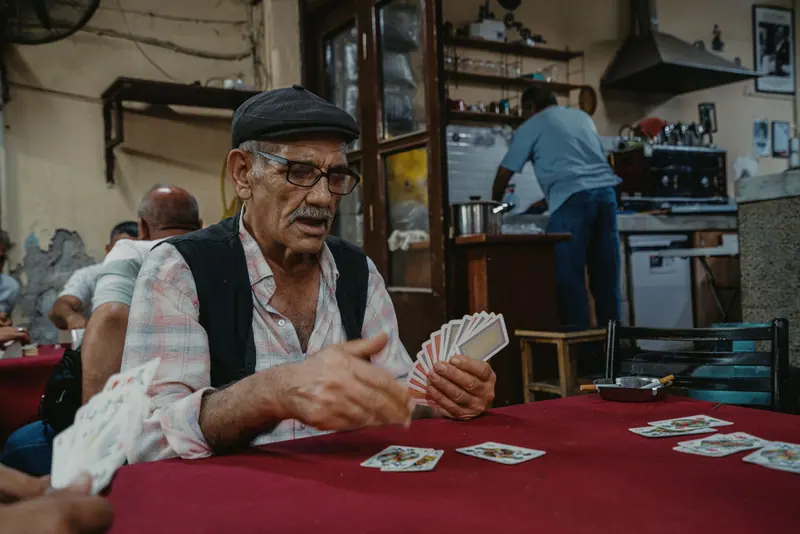 A member dealing a hand of cards at the red-topped table