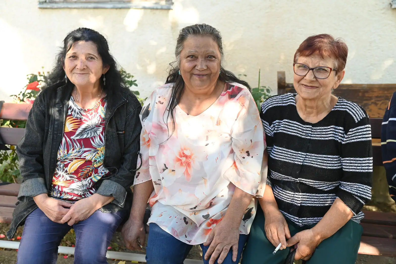 Three members smiling together on the garden bench after lunch
