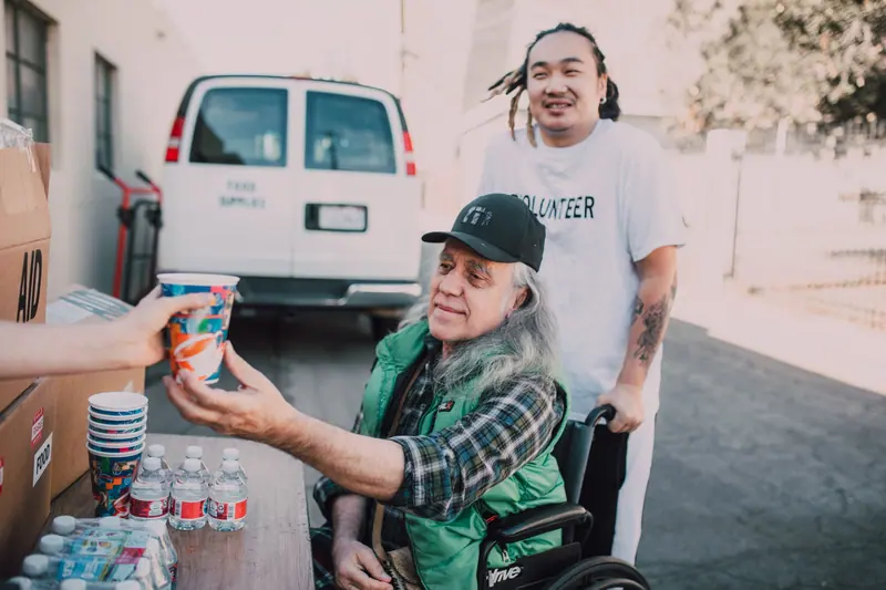 A volunteer handing a member a cold drink beside the van