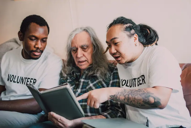 A volunteer reading with a member on the sofa