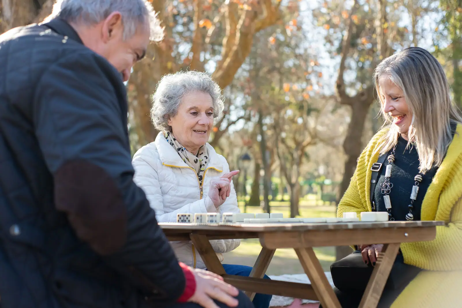 A member, her daughter and a staff member visiting over cards at the picnic table