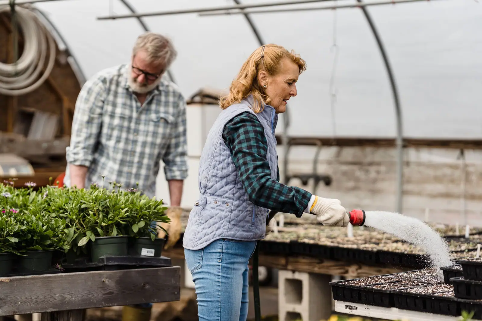 Two members tending seedlings together in the greenhouse behind the center