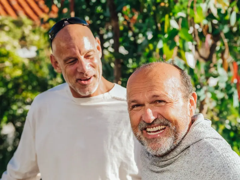 Two longtime friends laughing together in the courtyard sun