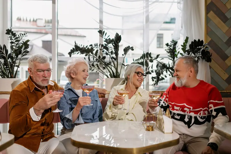 Elderly group enjoying drinks and smiles in a vibrant café.