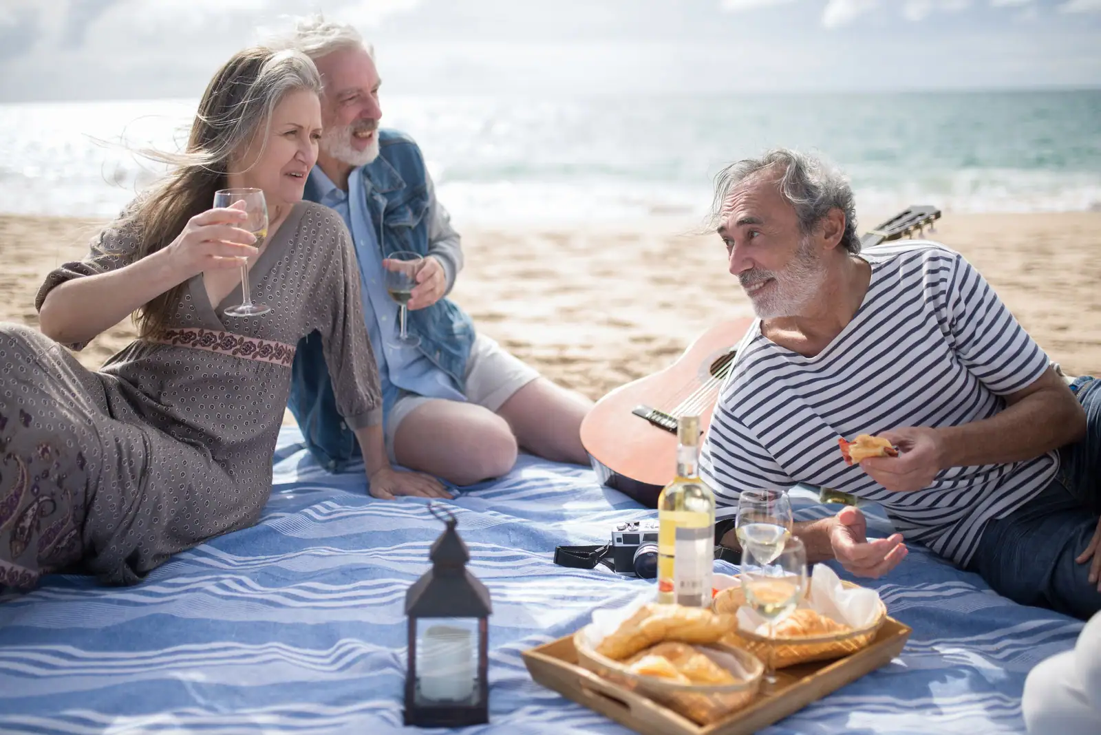 Members and a staff guitarist on a picnic blanket at the lake outing