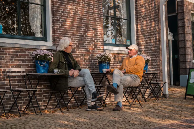 Two members trading stories over coffee on the patio