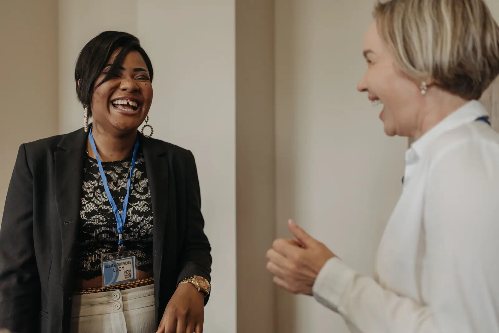 Two women sharing a joyful moment in a business meeting setting, fostering teamwork.