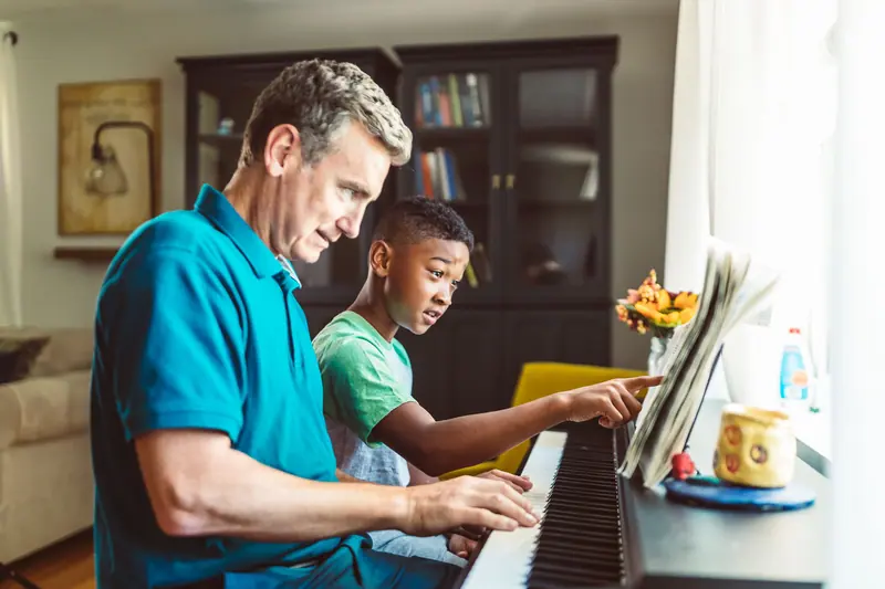 A resident teaching his grandson piano