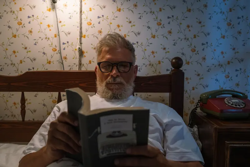 A resident reading in bed by lamplight