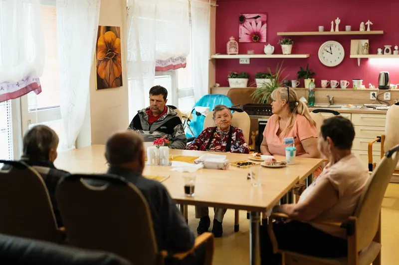 Residents and caregivers sharing lunch at the long dining table