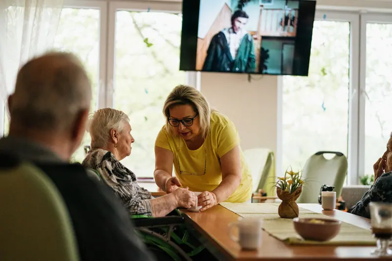A caregiver helping a resident at the lunch table