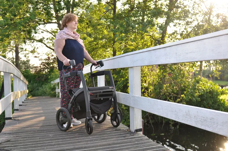 A resident crossing the footbridge over the pond with her rollator