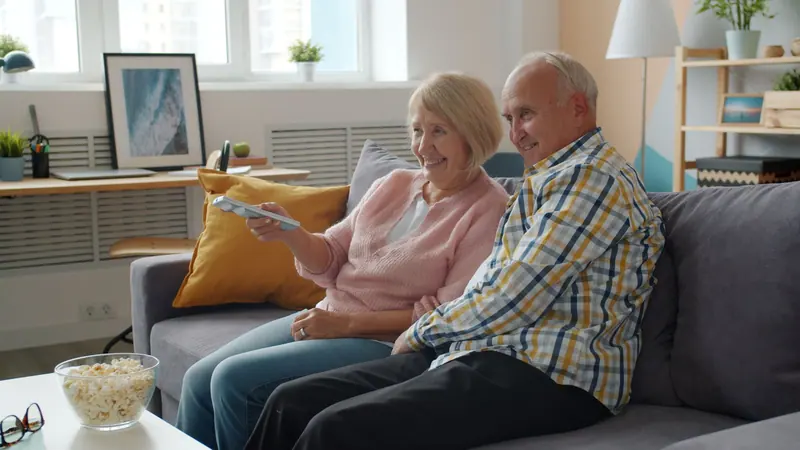 A resident couple laughing on the living room sofa