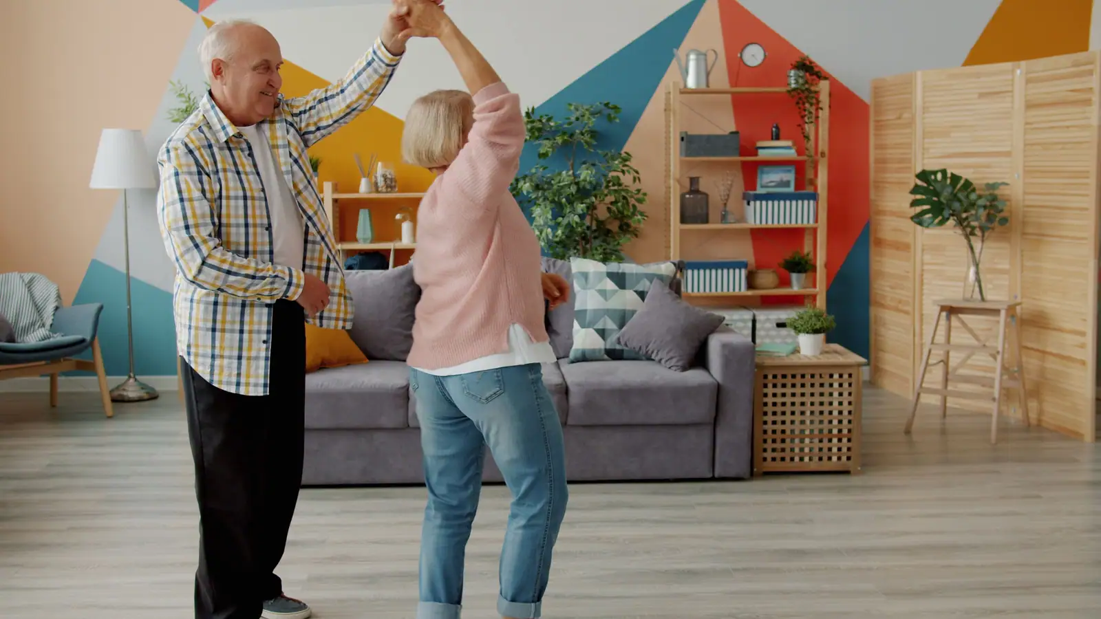A resident and her husband dancing in a bright living room painted in bold colors
