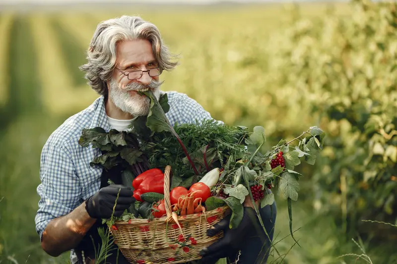 A resident holding a basket of peppers and tomatoes from the garden beds