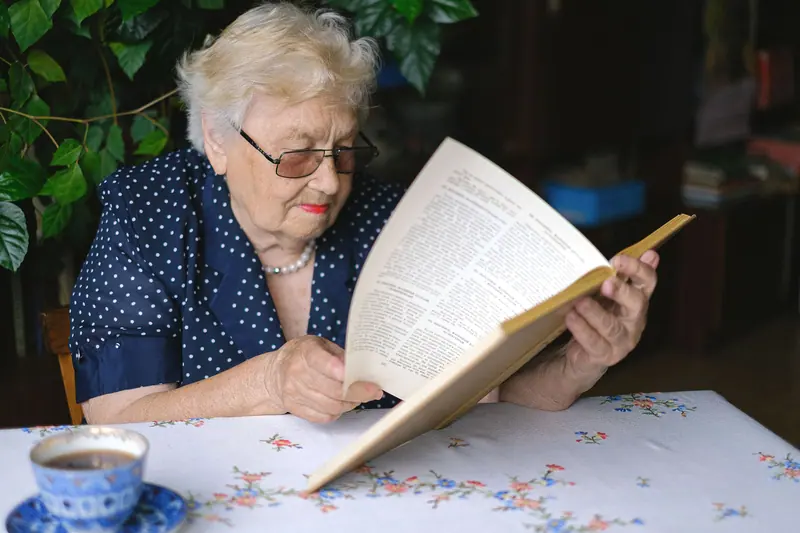 A resident reading in her apartment with a cup of tea beside her