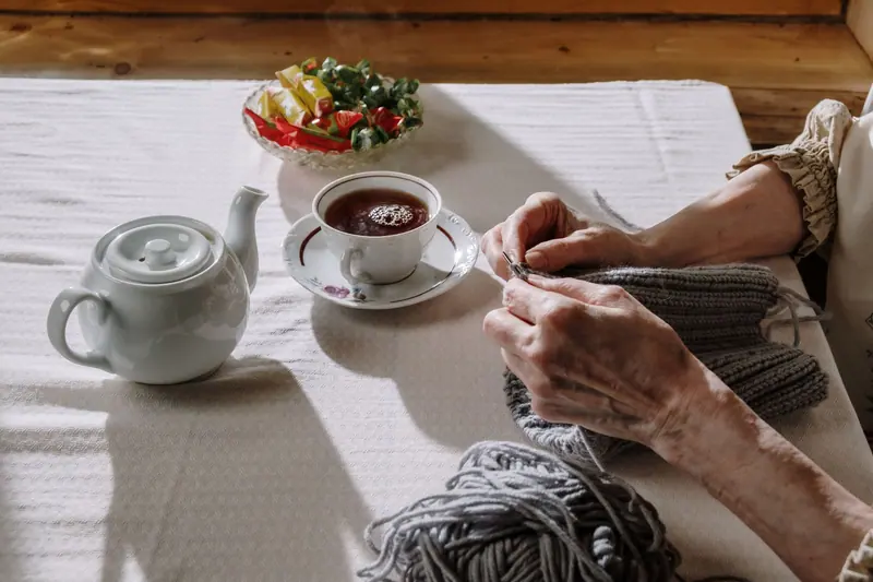 A resident knitting beside a pot of tea