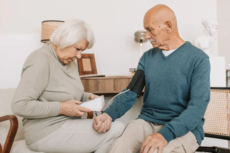 A resident and her husband checking his blood pressure