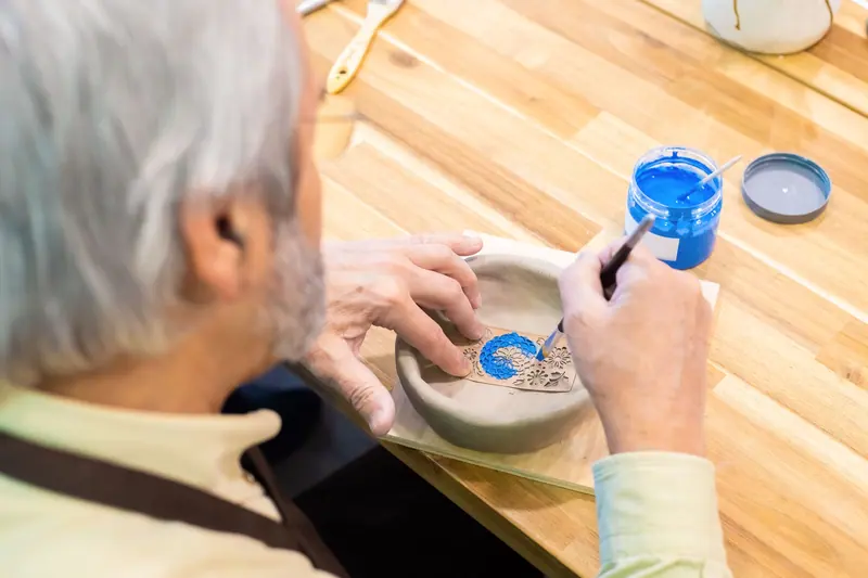 A resident painting a ceramic bowl