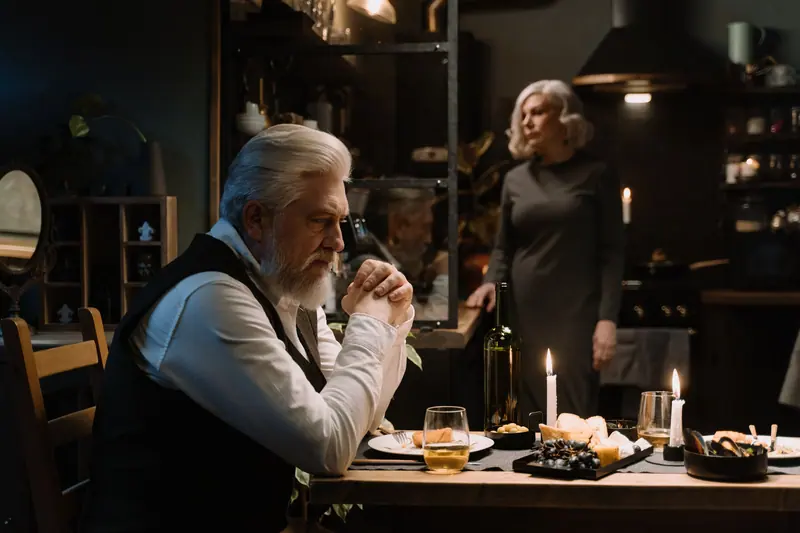 A couple lingering over a candlelit supper in their apartment
