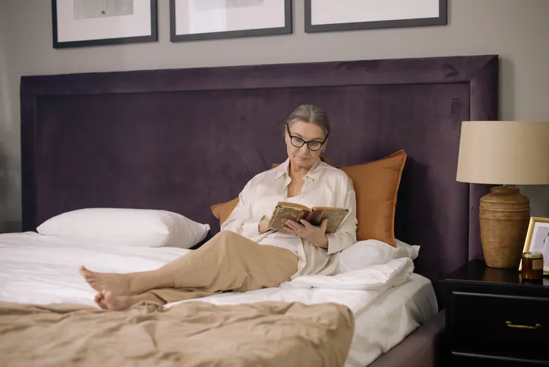 A resident reading on her bed against a purple headboard