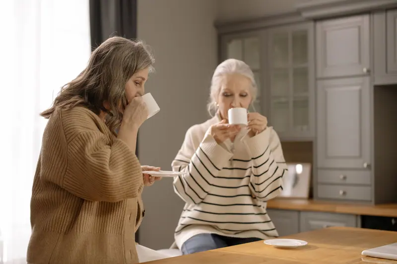 Two women sharing coffee and conversation at a kitchen table