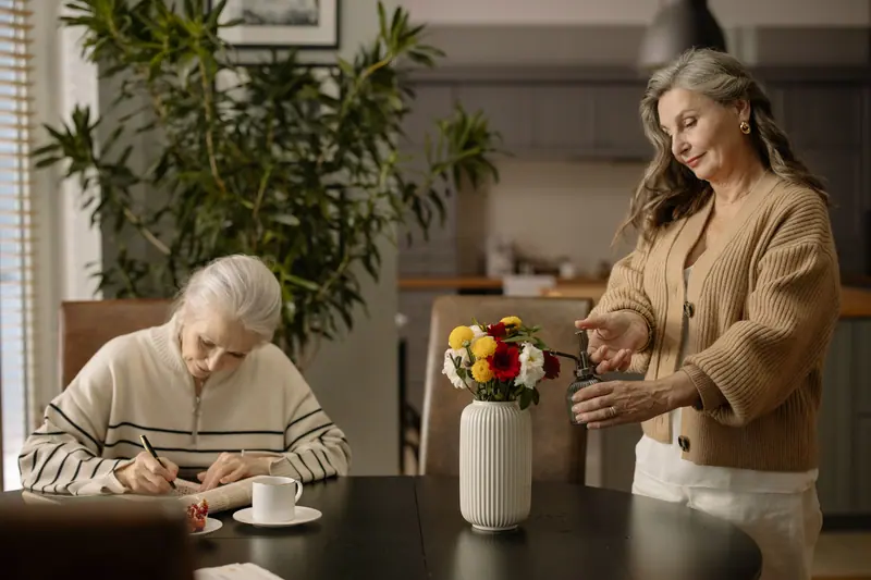 Two residents arranging fresh flowers on the dining room table