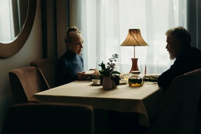 Two friends talking over a lamp-lit table