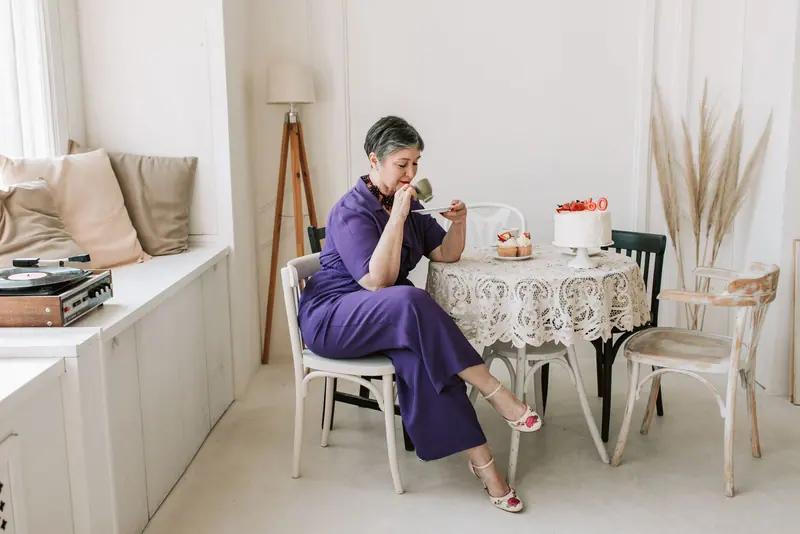 A resident enjoying birthday cake and coffee by the window seat