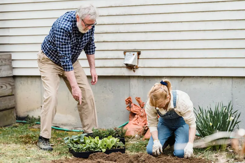 A resident and his daughter planting by the back wall