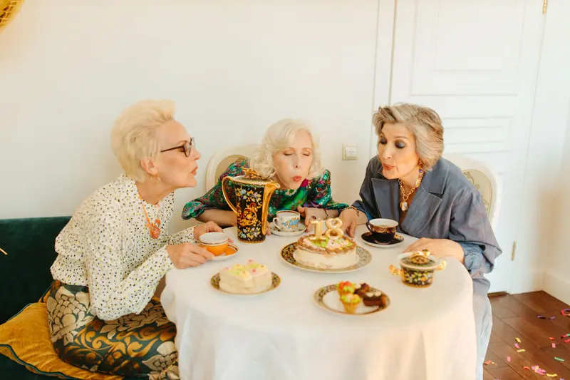 Three friends blowing out birthday candles at tea