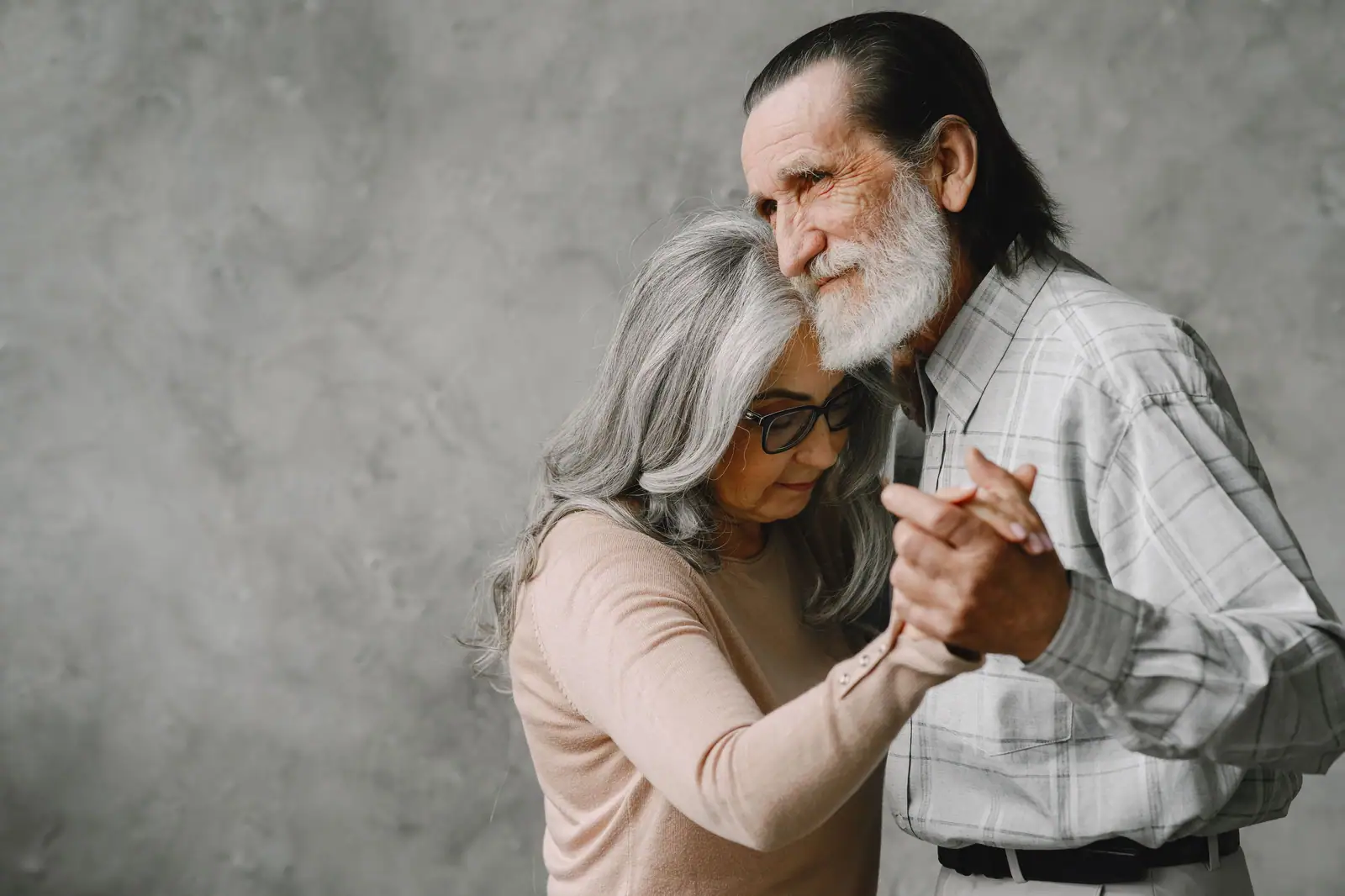 A silver-haired resident couple sharing a slow dance, her head on his shoulder