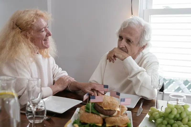 Two residents sharing burgers and grapes at a Fourth of July lunch