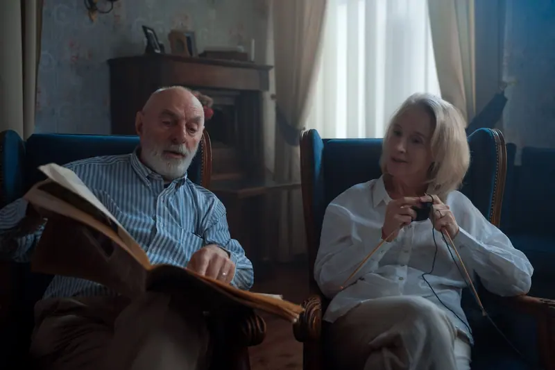 A couple reading and knitting side by side in the sitting room