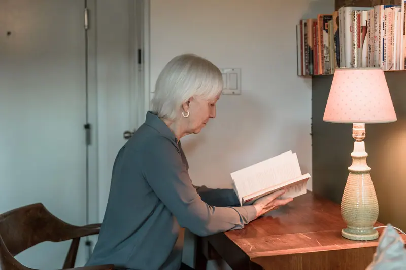 A resident reading at her lamp-lit desk