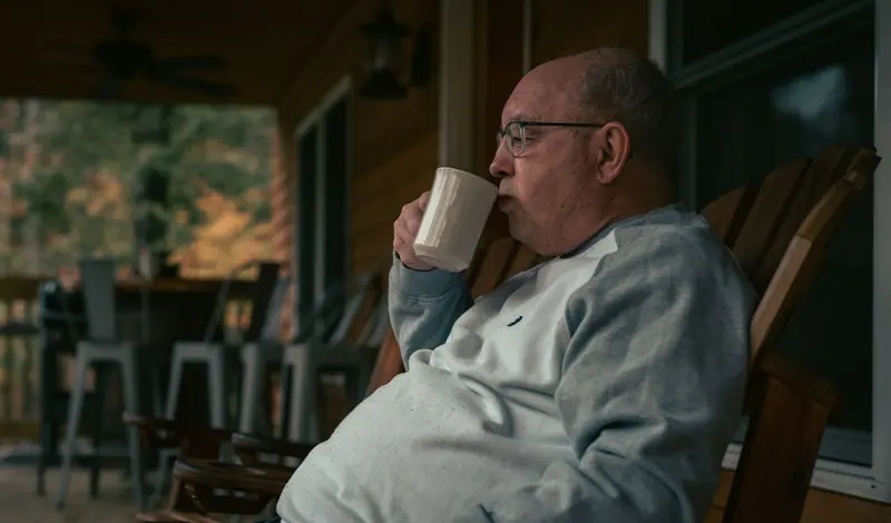 A resident with his coffee on the porch on an autumn morning