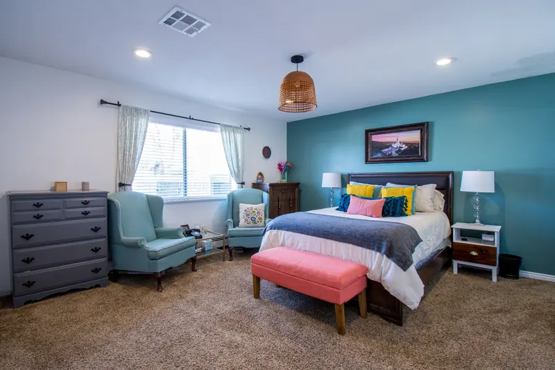 Modern bedroom with vibrant decor, featuring teal walls and comfortable furnishings.