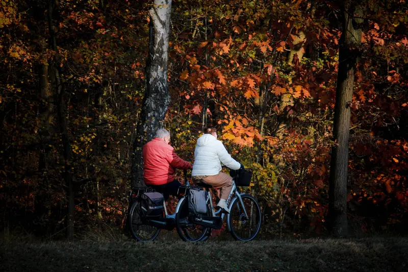 Two residents biking through autumn leaves