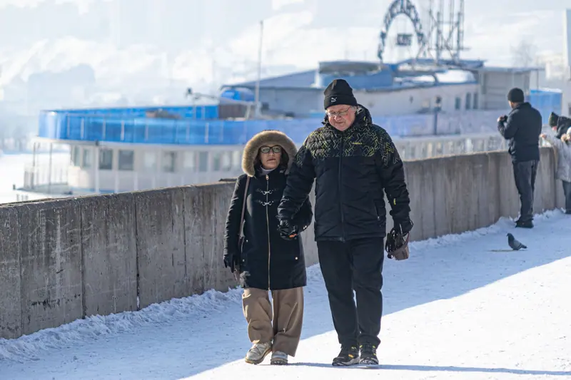 A couple holding hands on a snowy sidewalk