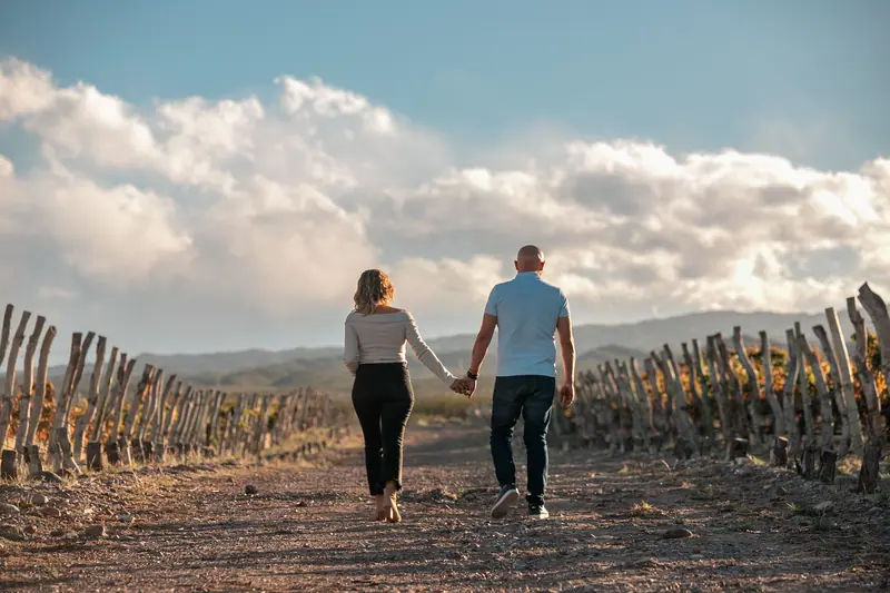 A couple walking hand in hand along the orchard path